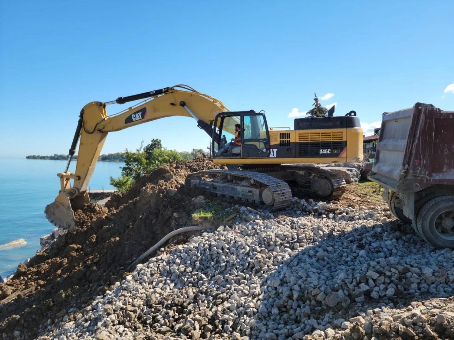 Crew placing armour stone along a shoreline